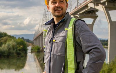 Firefly electrician looking proud at a bridge over a river, wearing protective gear and helmet; youn 2